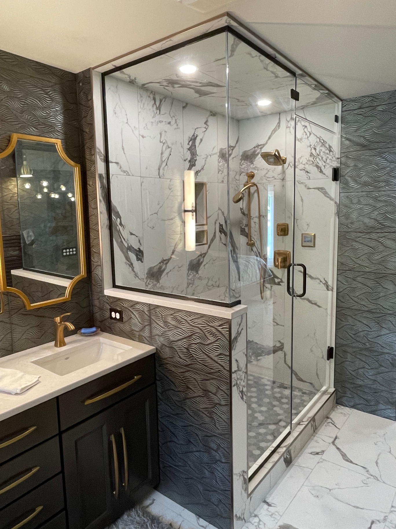Shower enclosure with black-trimmed glass panels, a swing door and marble tile beside a dark vanity
