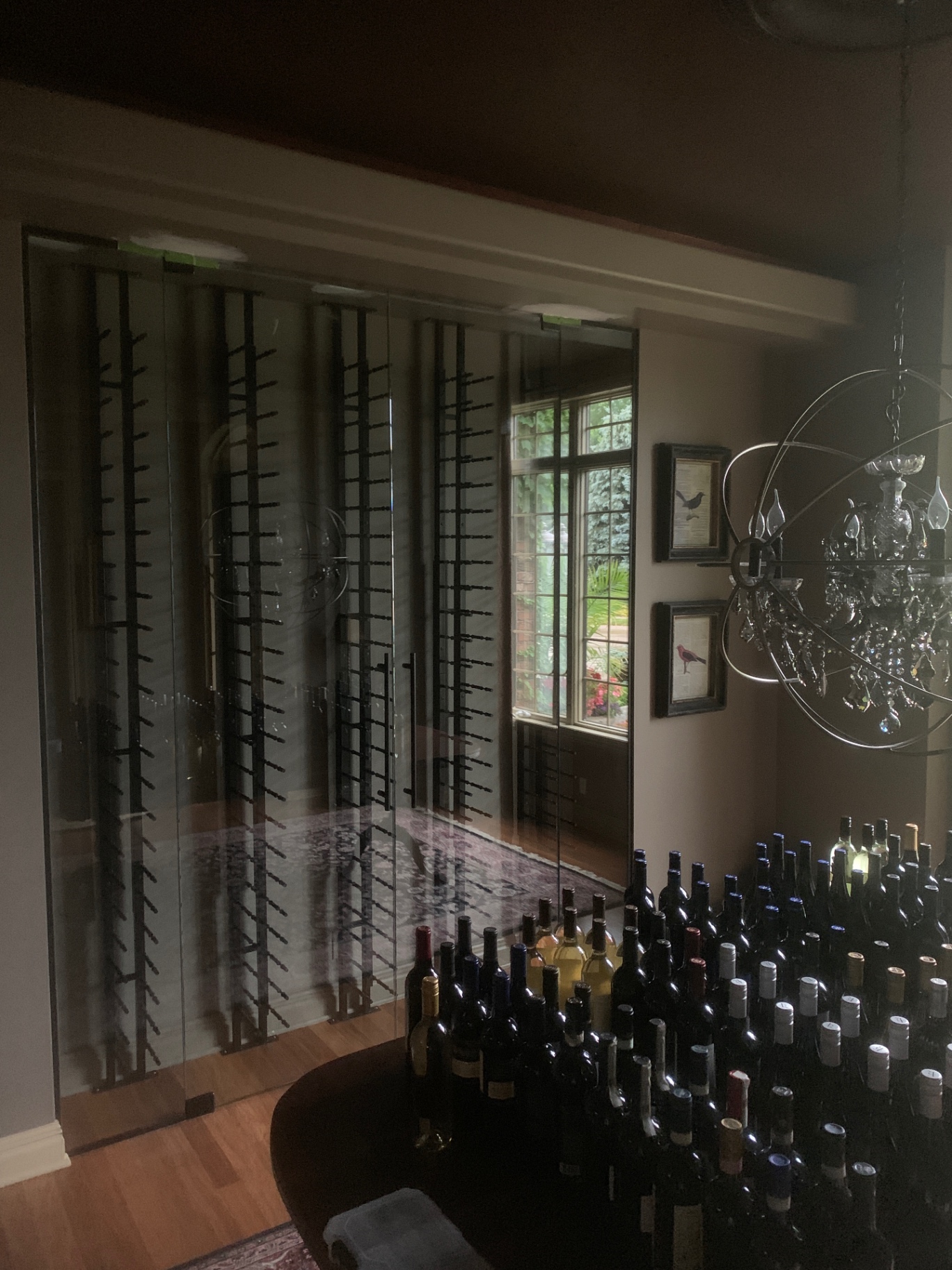 Sliding glass wine room doors enclosing black wall-mounted wine racks in a dining area